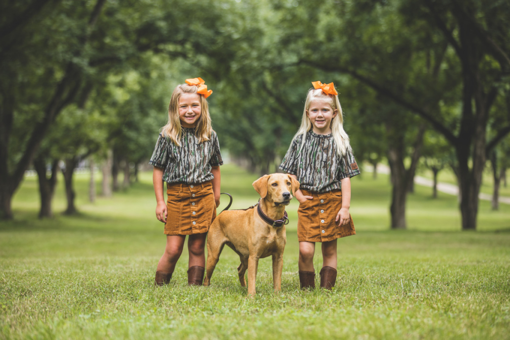 two girls wearing bc raskulls camo short sleeve t-shirts and their dog